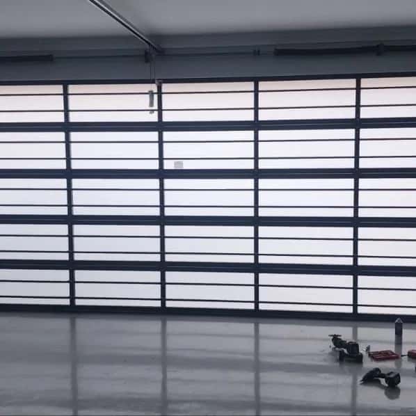 Daylight glowing through the frosted panels of a full-view glazed sectional door, seen from inside the garage