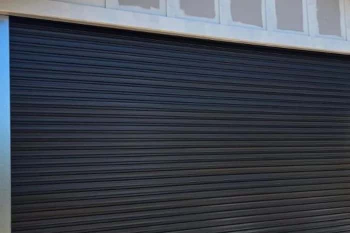 A black corrugated roller door, closed, beneath a cream fascia