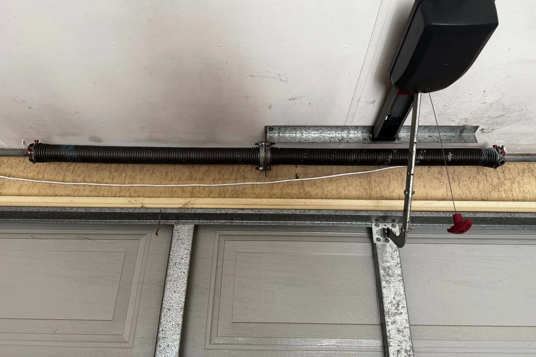 A new black torsion spring on the shaft above a grey sectional door