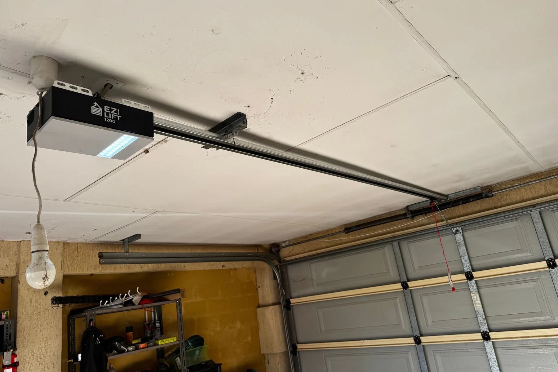 A new ceiling-mounted garage door opener on its rail, its light on