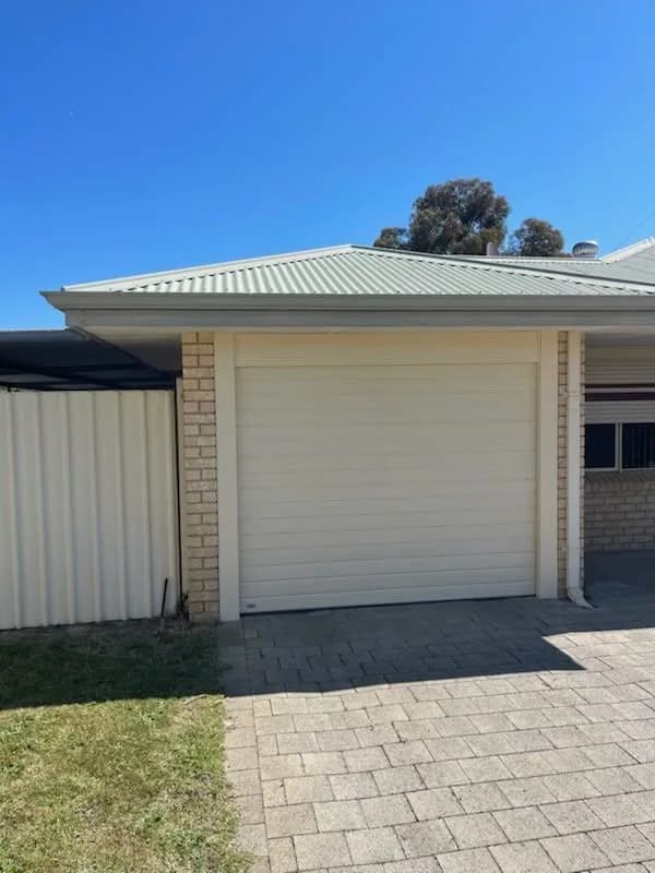 A new cream roller door on a single garage in full sun