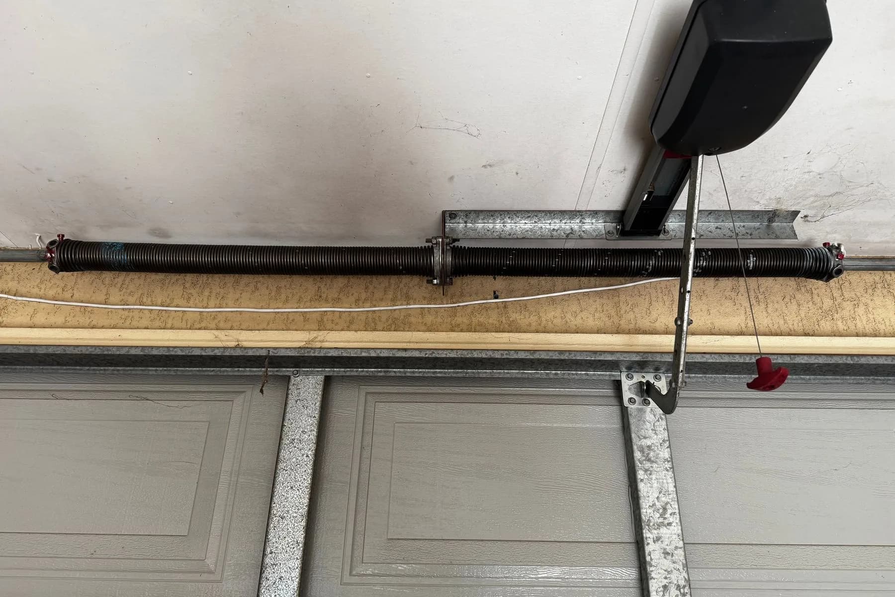 A new black torsion spring on the shaft above a grey sectional door