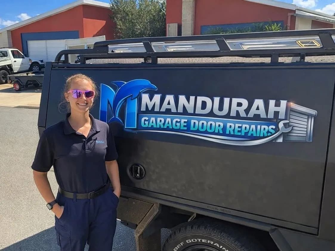 A technician standing beside the sign-written work ute outside a home