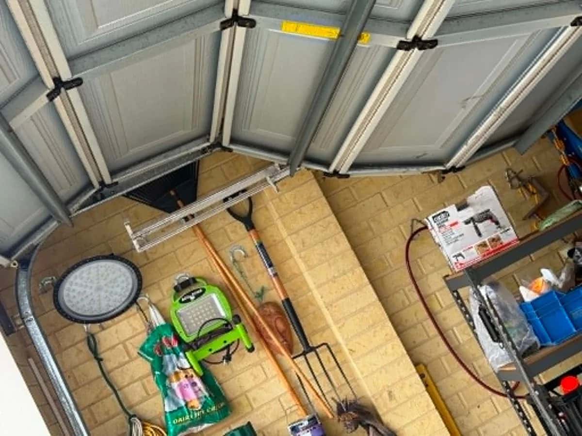 Sectional door panels folded and sagging away from the horizontal track inside a garage